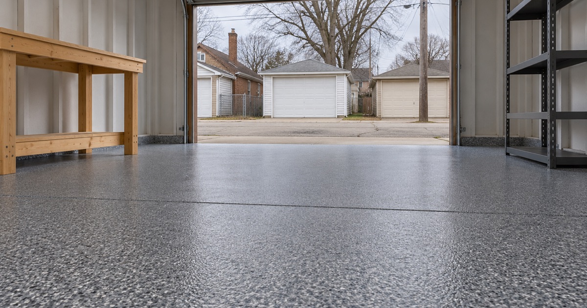 A finished, empty flake floor in a detached alley garage in Gary, Indiana, running clean from the back wall to the door threshold.